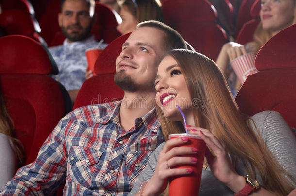 微笑的美丽的对拥抱和观察电影在电影院.