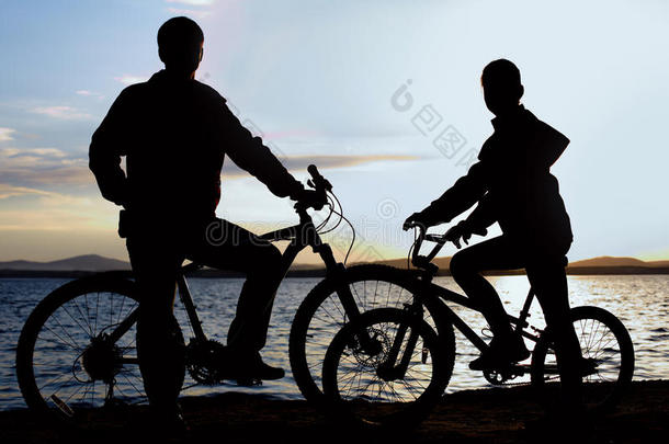 影像关于像运动家的家庭向自行车在户外反对日落.