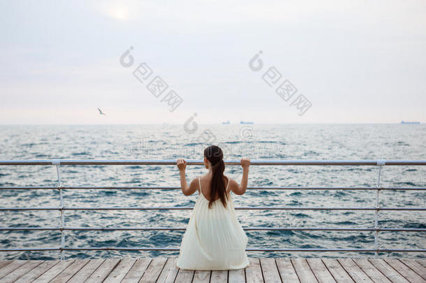 年幼的美丽的芭蕾舞女演员跳舞和使摆姿势在外面,海后面