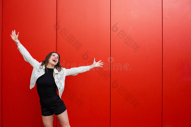 时髦的女人起立在近处红色的墙