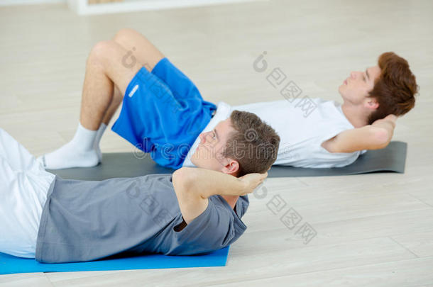两个男孩做仰卧起坐锻炼训练采用健身房