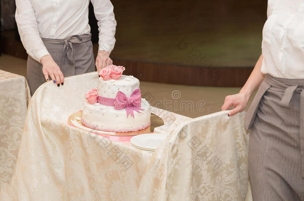 两个侍者支撑婚礼蛋糕和红色的玫瑰