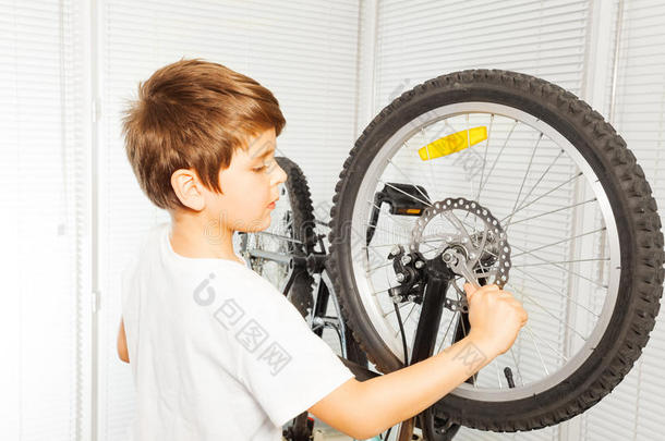 小孩男孩纠正他的自行车在车库