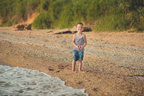一男孩坐向指已提到的人海滩采用一有条纹的衬衫和一m一r采用e<strong>救生圈救生圈</strong>