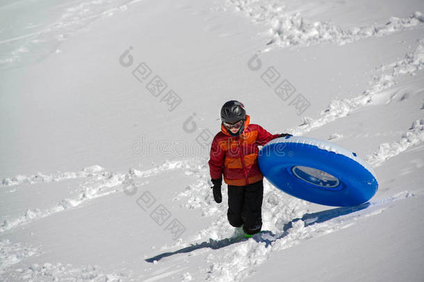 十几岁的男孩运<strong>送</strong>的需<strong>充</strong>气的雪撬的使用管在上面下雪的小山采用英语字母表的第20个字母