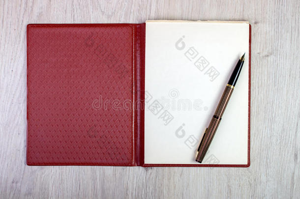敞开的笔记簿和白色的页和金人造喷泉笔
