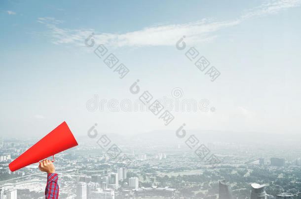 手关于女人佃户租种的土地红色的纸喇叭反对城市风光照片后面
