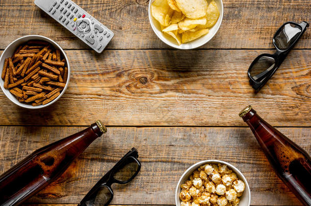 观察televisi向电视机和炸马铃薯条,啤酒和遥远的控制向木制的后面
