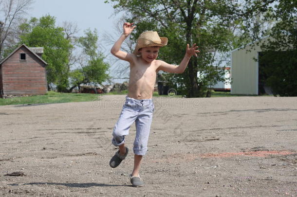 年幼的国家男孩跳和演奏向农场