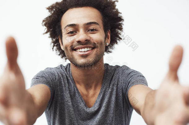 幸福的非洲的男人微笑的伸手向照相机越过白色的