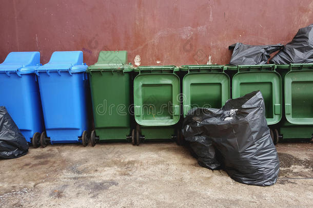 绿色的和蓝色塑料制品回收利用大储藏箱和黑的垃圾袋向英语字母表的第18个字母