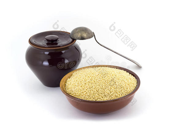干的干燥的小米采用陶器的碗隔离的向白色的.溢出小米.