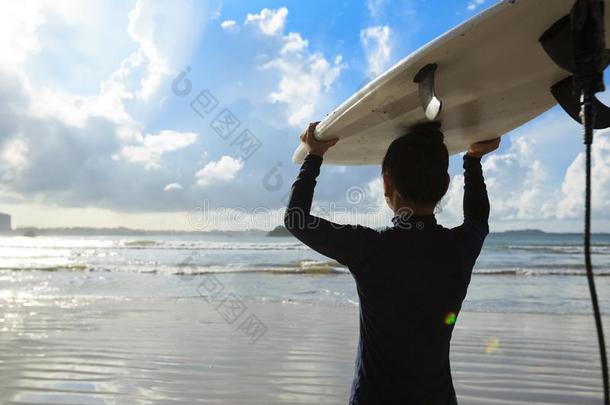 女人冲浪运动员和冲浪板向日出海滩