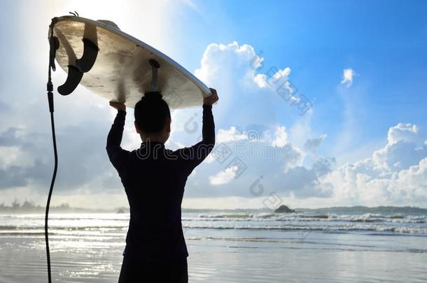 女人冲浪运动员和冲浪板向日出海滩