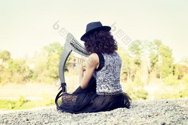美丽的有卷发的头发女人演奏指已提到的人竖琴