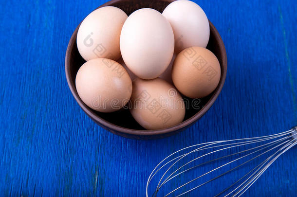 新鲜的卵采用一棕色的碗向蓝色b一ckground.顶看法