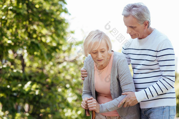 注意的老化男人支持的较高的妻子在户外