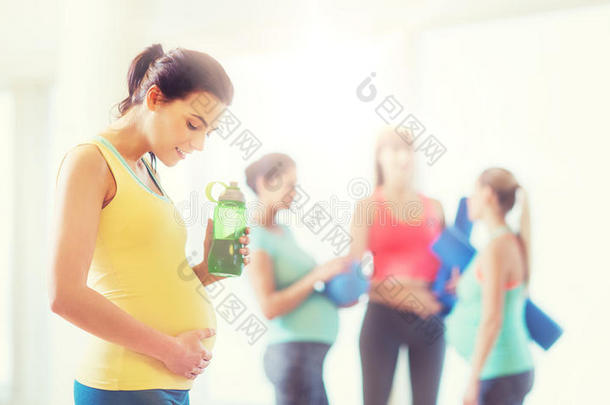 幸福的怀孕的女人和水瓶子采用健身房