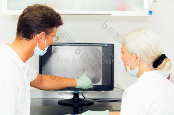牙科医生和助手有样子的在牙齿的字母x-射线