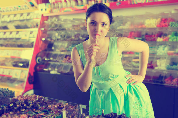 微笑的女孩吮吸糖果在糖果商店
