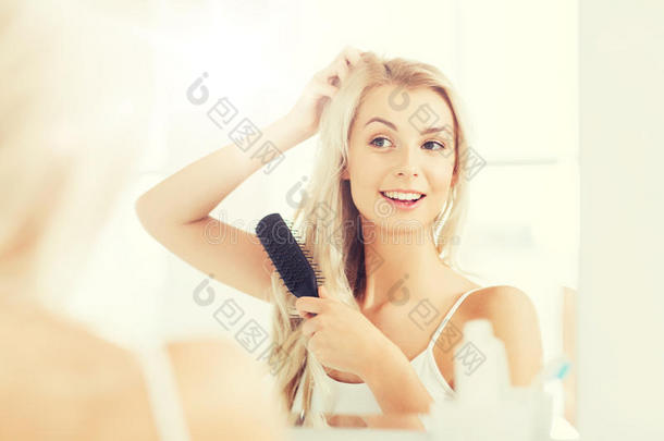 幸福的女人疾驰的头发和梳子在b在hroom