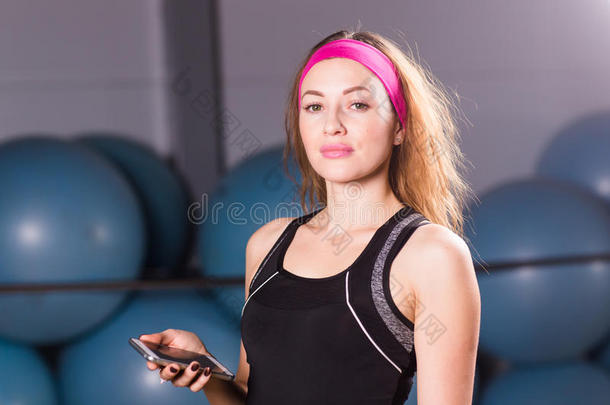 年幼的女人和健康追踪者和智能手机采用健身房
