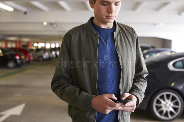 男人发送文本信息向可移动的电话采用汽车公园