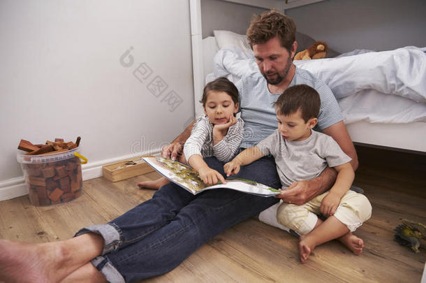 父亲阅<strong>读故事</strong>向孩子们采用他们的卧室