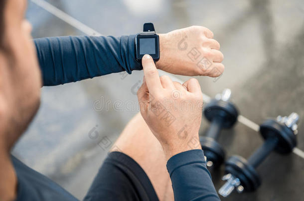 年幼的男人使用智能手表在健身房