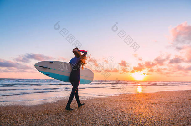 像运动家的海浪女孩走向海浪ing.女人和海浪board和日落