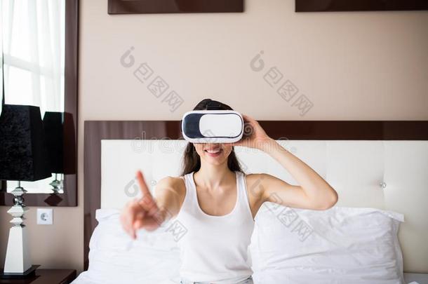 年幼的女人说谎向床,使用VirtualReality虚拟现实眼镜在家