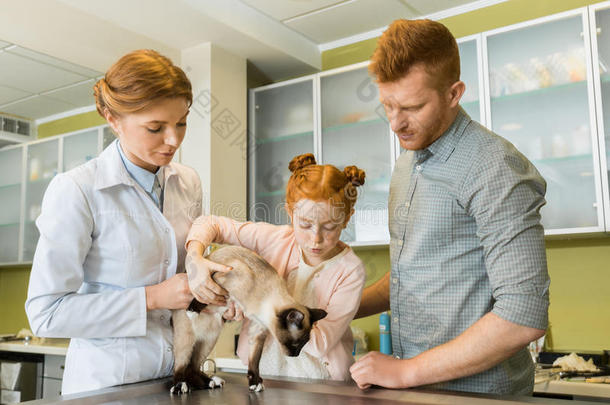 男人和他的女儿在兽医的医生和他们的宠物-支票