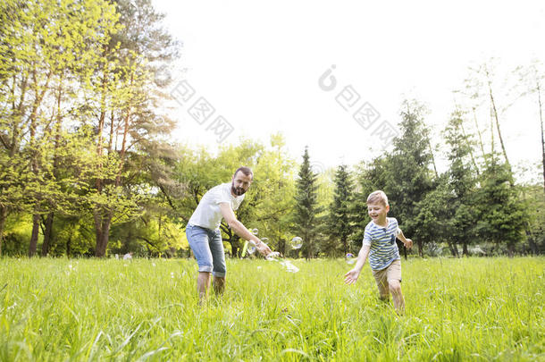 低到臀部的父亲和儿子吹风泡在户外采用公园.