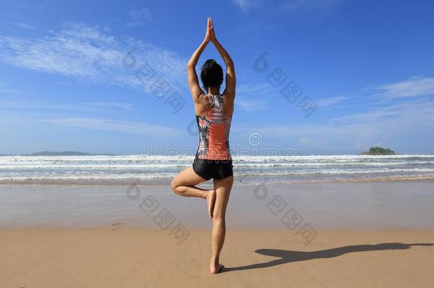 健康女人穿着游泳衣练习瑜伽向指已提到的人海滩