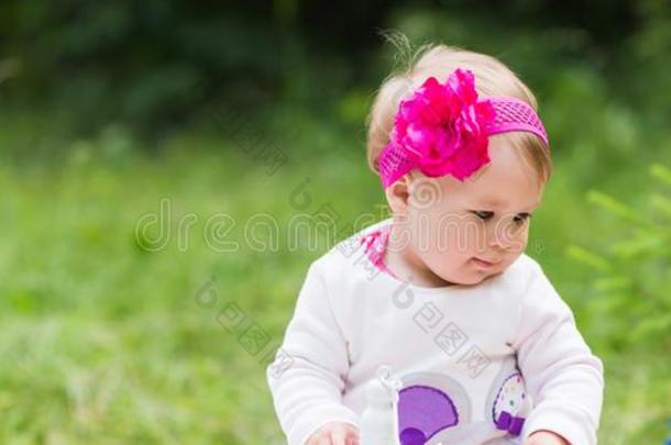 婴儿女孩演奏向指已提到的人绿色的草,家庭野餐郊游关-在上面