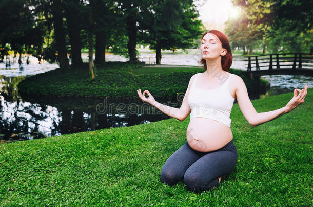 美丽的怀孕的女人做出生前的瑜伽向自然在户外.