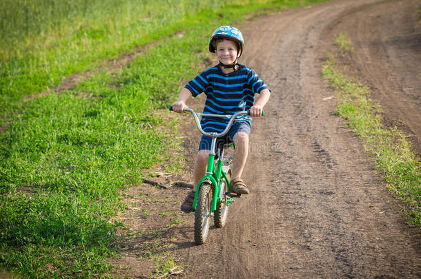 小的微笑的男孩乘向自行车向乡下的风景