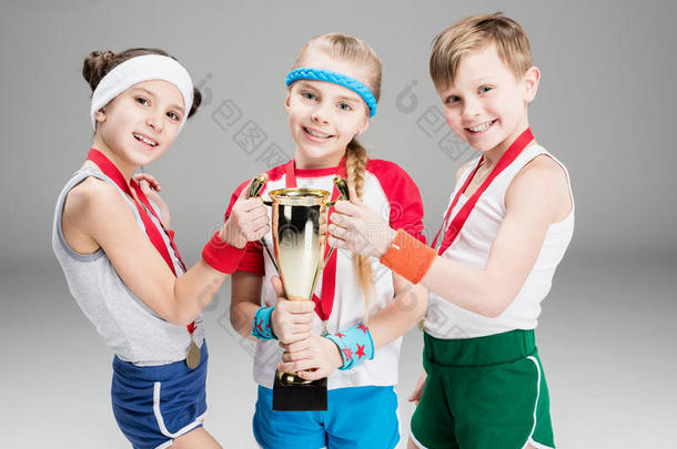 男孩和女儿和奖章和冠军高脚酒杯向灰色的