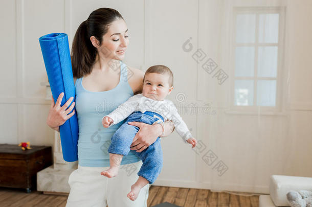 女人运送的她幸福的婴儿小孩向臂和佃户租种的土地瑜伽席子