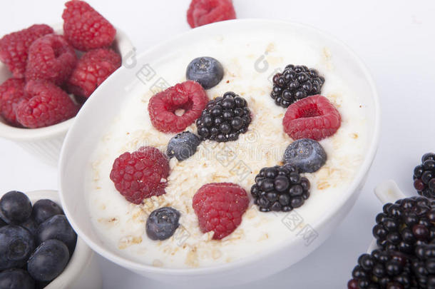 碗关于白色的酸奶和浆果和燕麦小薄片隔离的