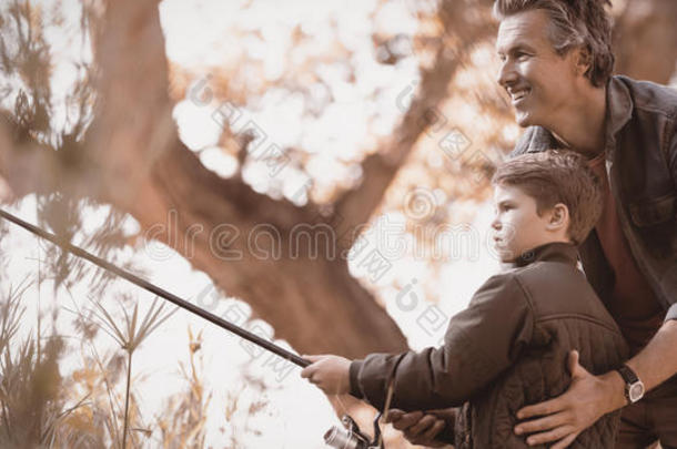 微笑的<strong>父亲帮助</strong>儿子在期间捕鱼采用森林