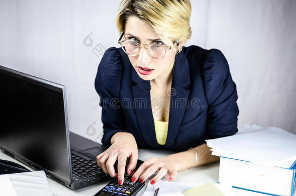 年幼的商业女人使用计算器