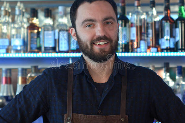一酒吧间男招待员在使工作微笑的和有样子的在照相机