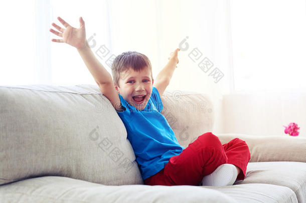 幸福的男孩增加手在期间一次向沙发