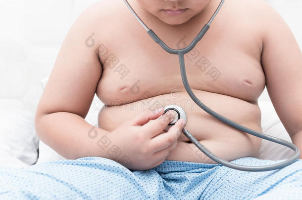 极为<strong>肥胖</strong>的肥的男孩检查胃在旁边听诊器.