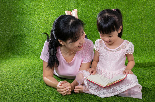 亚洲人中国人母亲和女儿阅读指已提到的人书