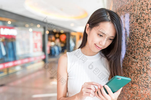 年幼的女人使用关于可移动的电话采用shopp采用g购物中心
