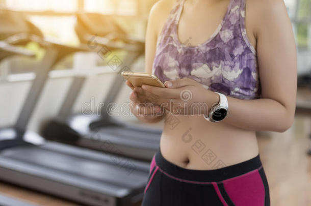 女人使用电话健康练习采用健身房聪明的小机械和运动