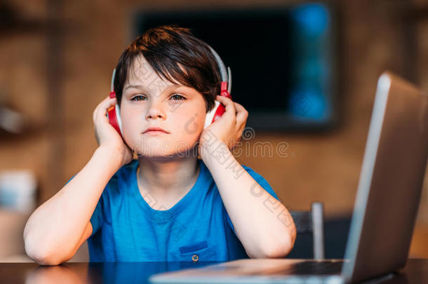 沉思的小的男孩收听的音乐采用耳机