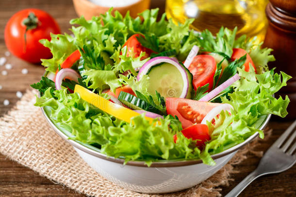 新鲜的蔬菜沙拉和绿叶蔬菜向木制的表.